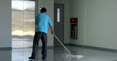 empleado de una empresa de limpieza limpiando el piso con un escobillon en un edificio de consorcio